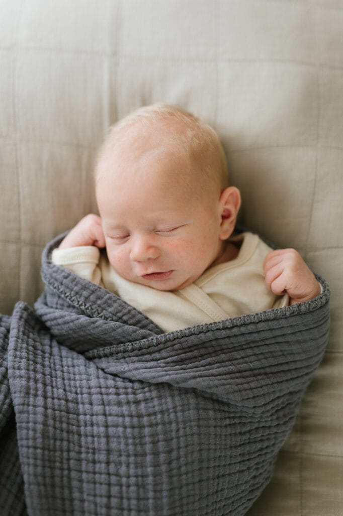Natürliche Babyfotografie mit schmunzelndem Neugeborenen bei einer Homestory in Berghaupten.
