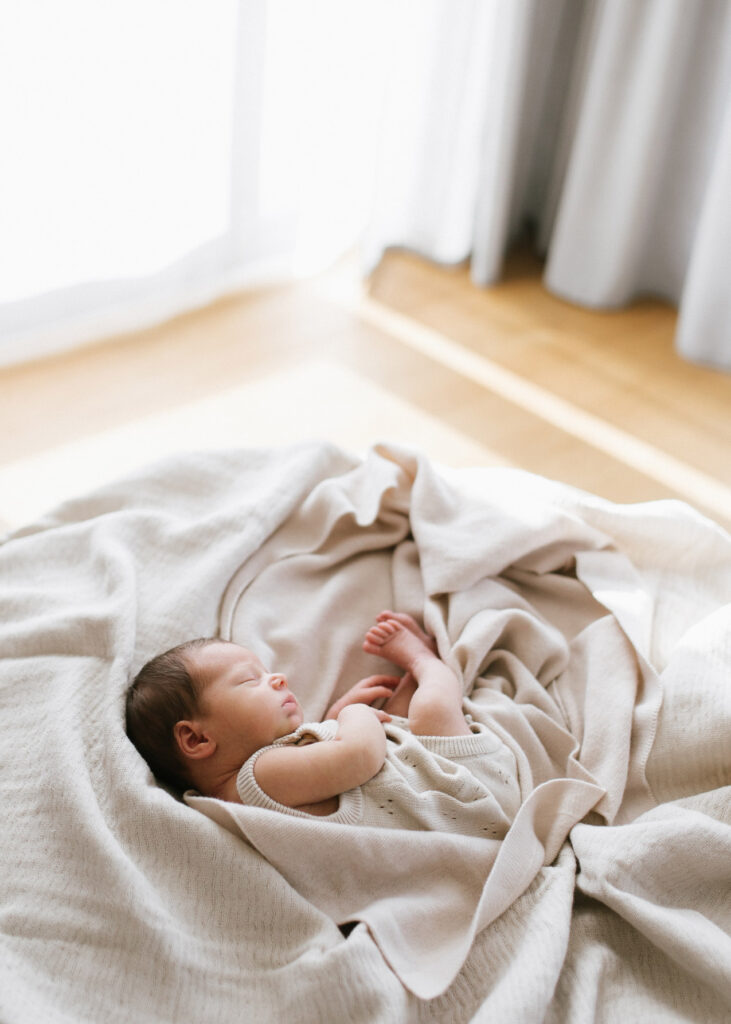 Baby in Decken auf einem Beanbag in natürlichem Licht bei einer Neugeborenen-Homestory in Offenburg.