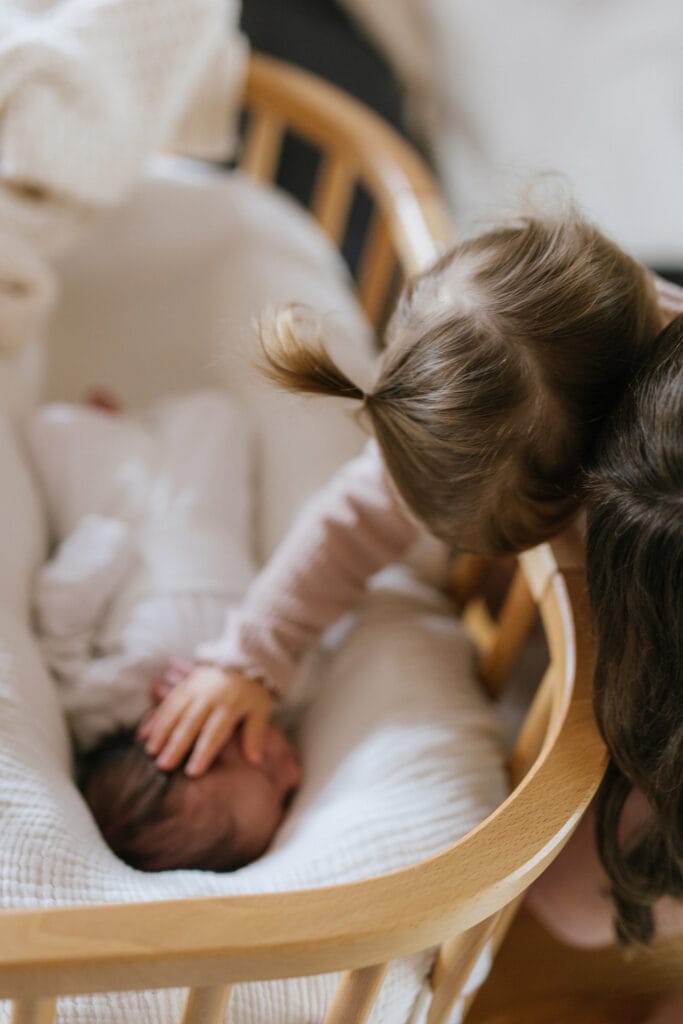 Große Schwester streichelt liebevoll das Baby in der Wiege in Gengenbach.