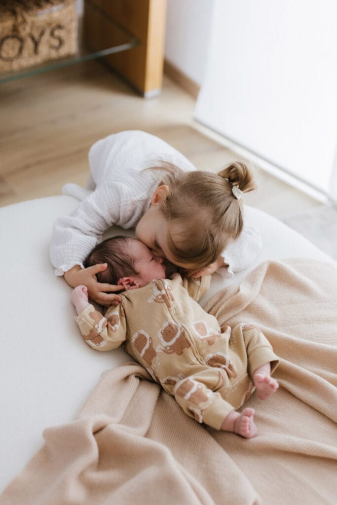 Liebevoll umarmt die Schwester ihren Bruder bei einem Neugeborenen-Fotosession in Offenburg.