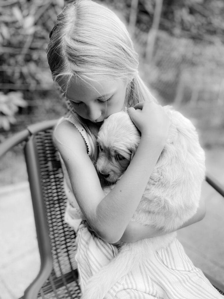 Ein Mädchen mit einem Hundewelpen auf dem Arm.